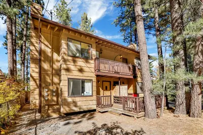 a log home with a balcony and a tree at Buttercup Snow Summit Condo by Big Bear Vacations in Big Bear Lake