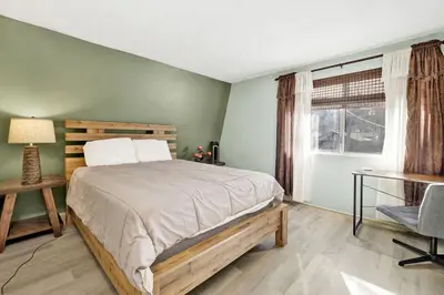 a bedroom with a bed and a desk and a window at Aeroplane Gambrel Chalet- Adorable Airport Retreat Cottage in Big Bear City