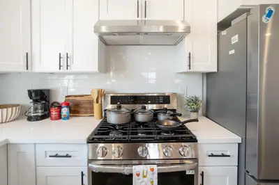 a kitchen with white cabinets and a stove top oven at Urban Oasis in the Heart of LA Near USC & Major Attractions in Los Angeles