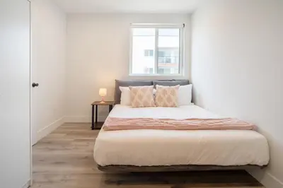 a white bedroom with a large bed with a window at Urban Oasis in the Heart of LA Near USC & Major Attractions in Los Angeles