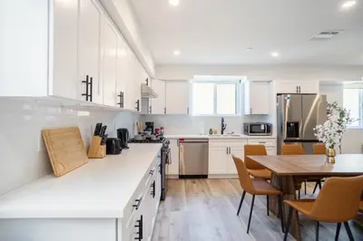 a kitchen with white cabinets and a wooden table at Chic & Comfortable Space Near Downtown LA & USC in Los Angeles