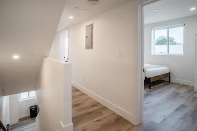 a white hallway with a stairway leading to a bedroom at Stylish & Cozy Retreat Near USC & Downtown LA in Los Angeles
