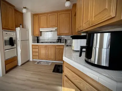 a kitchen with wooden cabinets and a white refrigerator at gateway to the ocean in Hawthorne