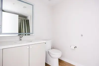 a white bathroom with a toilet and a mirror at Blueground Downtown elevator nr parks LAX-1235 in Los Angeles
