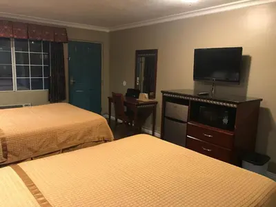 a hotel room with two beds and a flat screen tv at Corona inn in Corona