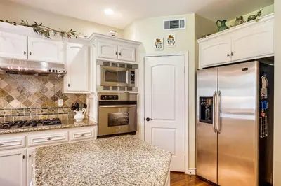 a kitchen with white cabinets and a stainless steel refrigerator at 6 Mi to Dtwn Pasadena Home with Patio and Yard! in San Gabriel