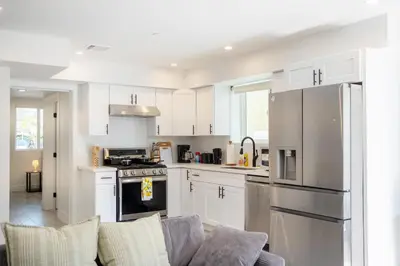 a kitchen with white cabinets and a couch at Cozy LA Retreat Near USC Steps to Koreatown & Downtown in Los Angeles