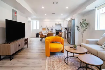 a living room with a tv and a yellow chair at Cozy LA Retreat Near USC Steps to Koreatown & Downtown in Los Angeles