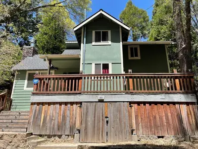 a house with a wooden fence in front of it at Calm Cozy 3BR cabin wAC, WiFi, Parking, BBQ in Cedar Glen