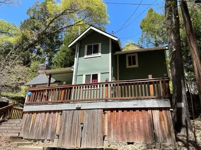 a house with a wooden fence in front of it at Calm Cozy 3BR cabin wAC, WiFi, Parking, BBQ in Cedar Glen