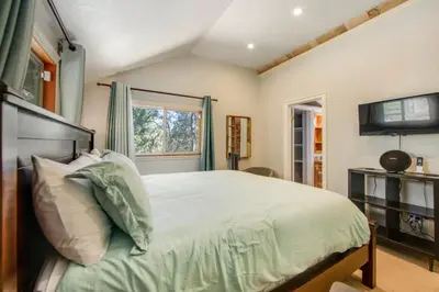 a bedroom with a large bed and a window at Calm Cozy 3BR cabin wAC, WiFi, Parking, BBQ in Cedar Glen