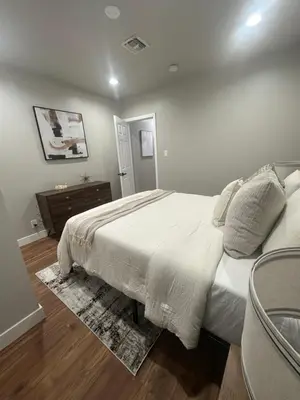 a bedroom with a white bed and a wooden floor at Stylish & Cozy Retreat in the Heart of LA in Los Angeles