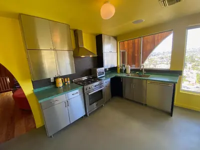 a kitchen with stainless steel appliances and a yellow wall at The Bernardi House in Los Angeles
