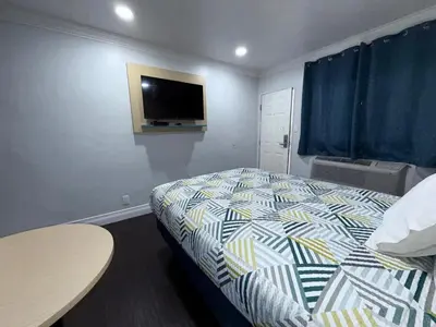 a bedroom with a bed and a tv on the wall at Uptown Inn in Long Beach