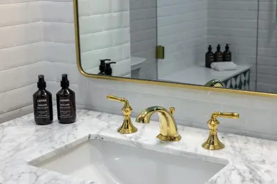 a bathroom sink with two faucets and a mirror at Whisky Hotel in Los Angeles