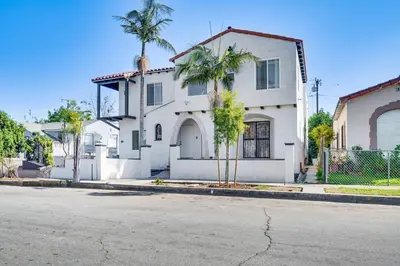 a white house with palm trees in front of a street at 7 Mi to Downtown East Los Angeles Apartment in East Los Angeles