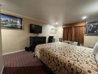 a hotel room with a bed and a flat screen tv at Sunrise Inn in Gardena