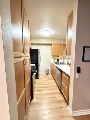 a kitchen with a stainless steel refrigerator and wooden cabinets at Oceanfront 1 BR Oasis w Parking & Pool 417 in Redondo Beach