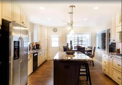 a kitchen with white cabinets and a island with a table at Tiki House and Spa - Walking Distance to Dsineyland in Anaheim