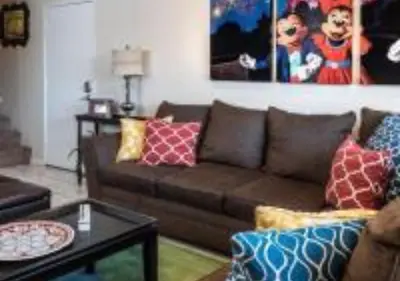 a living room with a brown couch and a table at Magicway Villas Mini's Poolside and Spa - Across Disneyland in Anaheim
