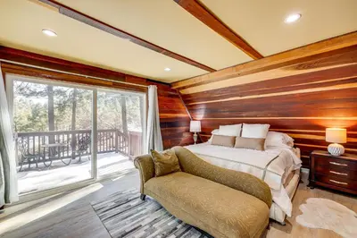 a bedroom with wooden walls and a bed and a chair at Wraparound Deck and Grill Wrightwood Cabin Near PCT in Wrightwood