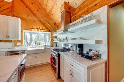 a kitchen with wooden ceilings and a stove top oven at Wraparound Deck and Grill Wrightwood Cabin Near PCT in Wrightwood