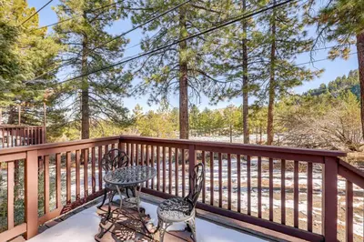 a patio with two chairs and a table on a deck at Wraparound Deck and Grill Wrightwood Cabin Near PCT in Wrightwood