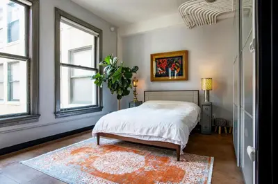 a bedroom with a bed and two windows and a rug at City Lights Loft Downtown LA Month Plus in Los Angeles