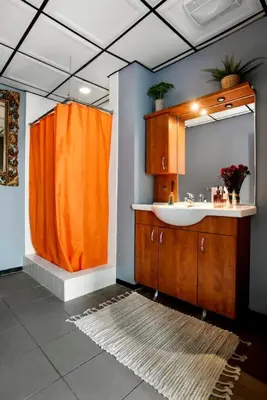 a bathroom with an orange shower curtain and a sink at City Lights Loft Downtown LA Month Plus in Los Angeles