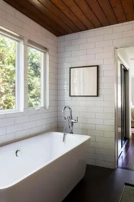 a white tub in a bathroom with two windows at Sun-Drenched Spanish Manor Home in Mar Vista in Los Angeles