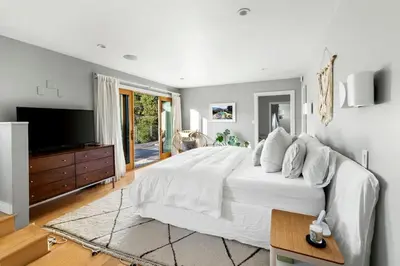 a bedroom with a large white bed and a flat screen tv at Hillside Hideaway with Deck And Spa in Topanga Canyon in Topanga