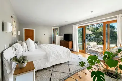 a bedroom with a white bed and a balcony at Hillside Hideaway with Deck And Spa in Topanga Canyon in Topanga