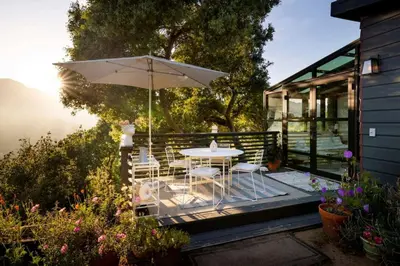 a patio with a table and chairs and an umbrella at Canyon Crest Cottage and Garden in Topanga Canyon in Topanga