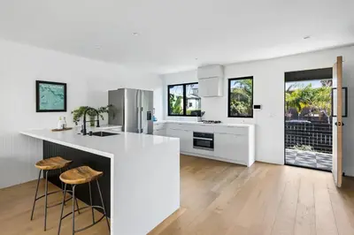 a white kitchen with a large island and stools at Westminster Bungalow - Front House with Private Entrance in Los Angeles