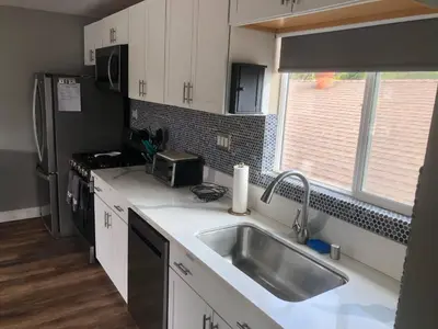 a kitchen with white cabinets and a sink and a window at The Lookout in Los Angeles