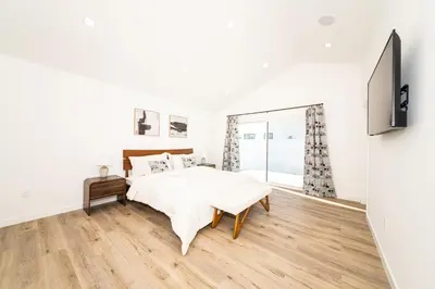 a white bedroom with a bed and a flat screen tv at A Brand New Home In Los Angeles in Van Nuys County Court Heliport