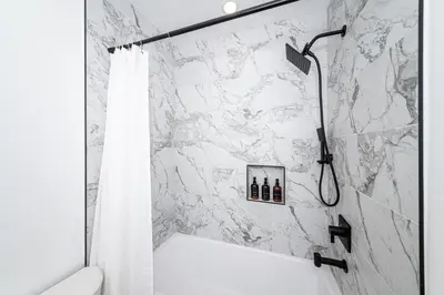 a bathroom with a shower with a white marble wall at A Brand New Home In Los Angeles in Van Nuys County Court Heliport