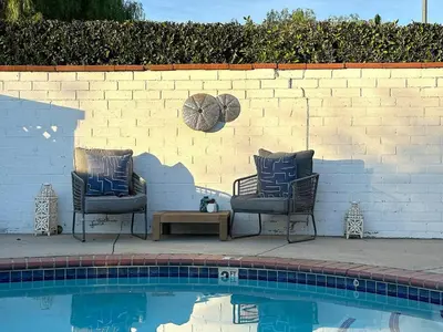 two chairs and a table next to a swimming pool at Tranquil Poolside Oasis with BBQ and Serene Ambiance in North Hollywood