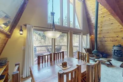 a dining room with a wooden table and a large window at Whistle Stop Cabin in Lake Arrowhead