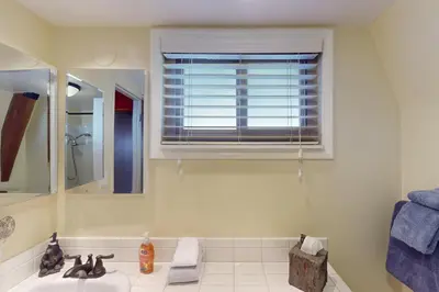 a bathroom with a sink and a mirror and a window at Whistle Stop Cabin in Lake Arrowhead