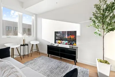 a living room with a couch and a tv on a wall at Bright Studio on Sunset Blvd, Free Parking, Gym, and Pool in Los Angeles
