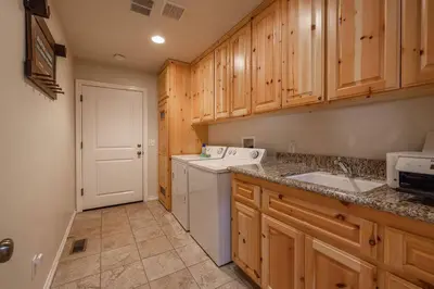 a kitchen with wooden cabinets and a washer and dryer at TimberWood Cabin- 3 Bdr - 2 Bth - Big Game room - Prime Location in Big Bear Lake in Big Bear Lake