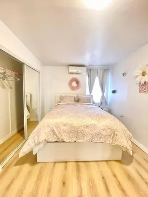 a bedroom with a bed and a wooden floor at 1BR Pink Cozy House near DTLA in Rosemead