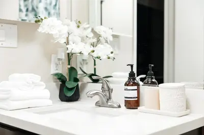 a bathroom counter with a sink with a vase of flowers at Signature One Bedroom Apartment in Los Angeles