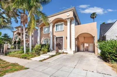 a large house with palm trees and a driveway at Spacious 2BR Apartment with Full Kitchen & Dining In Beverly Hills in Los Angeles