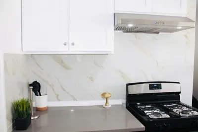 a kitchen with a stove and white cabinets at Los Angeles Red Rose in Monterey Park