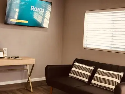 a living room with a couch and a tv on the wall at Noah Unit - B in Hawthorne
