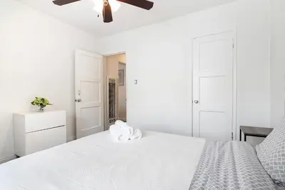 a white bedroom with a bed with a ceiling fan at Ground-Floor 1-Bedroom by Beverly Hills Steps from Restaurants, Cafes and Shopping in Los Angeles
