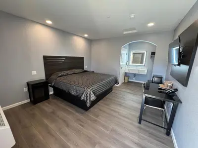 a bedroom with a bed and a table and a desk at Dutch Motel in Loma Linda