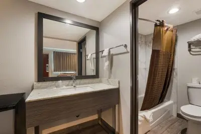 a bathroom with a sink and a toilet and a mirror at Rodeway Inn San Bernardino and Redlands in San Bernardino